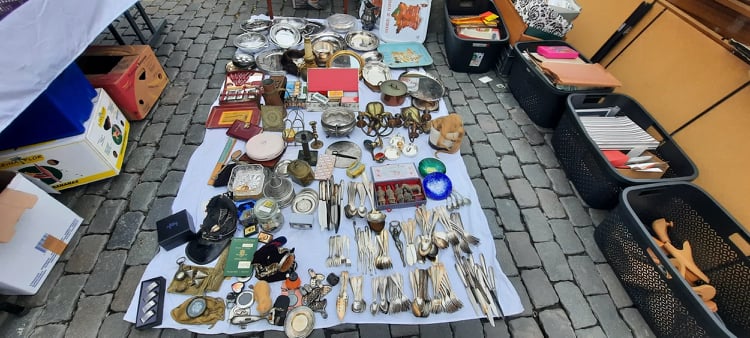 Zilverwerk, bestek, horloges en kleine antiquiteiten uitgestald op een doek op een rommelmarkt.