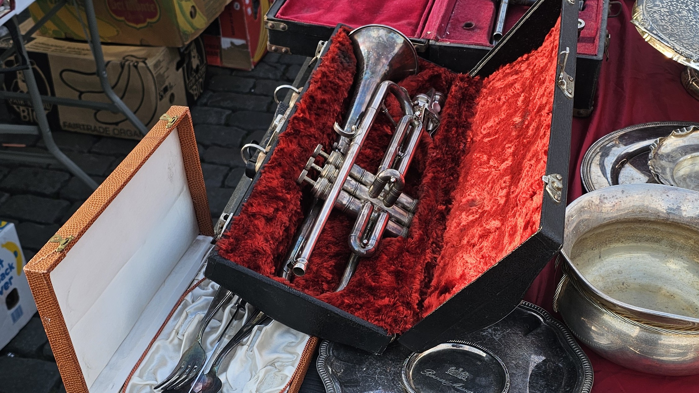 Trompette dans son étui de velours rouge et plats en métal argenté au marché aux puces du Jeu de Balle, à Bruxelles